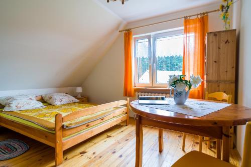 een slaapkamer met een bed, een tafel en een raam bij Wigierska Zagroda - agroturystyka in Suwałki