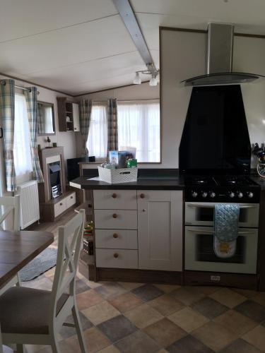 a kitchen with a stove and a table in it at BRANWOOD Luxury Caravan Holidays Newquay in Newquay