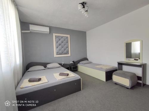 Habitación con 2 camas, TV y espejo. en Къща за гости Атмосфера, en Tsarevo