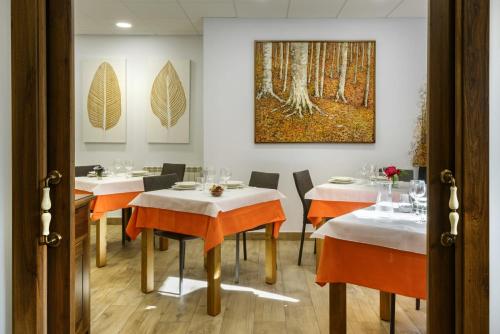 a dining room with white tables and orange chairs at Hostal Bosque de Gamueta in Ansó