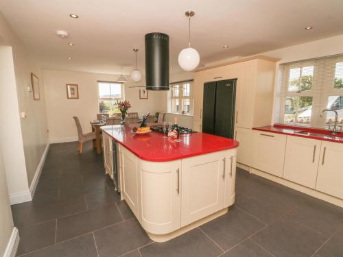 a large kitchen with a red counter top at Dereside in Hexham