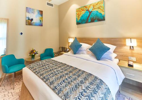 Rose Plaza Hotel Al Barsha في دبي: غرفه فندقيه بسرير وكرسيين ازرق