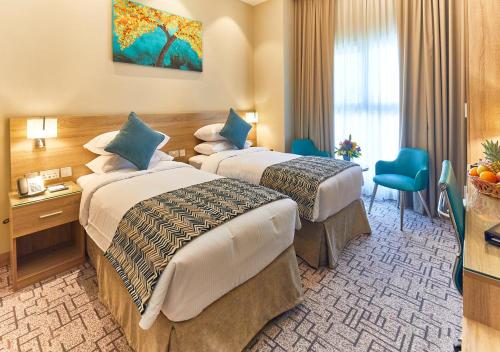 a hotel room with two beds and a desk at Rose Plaza Hotel Al Barsha in Dubai