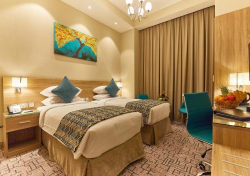 a hotel room with two beds and a desk at Rose Plaza Hotel Al Barsha in Dubai