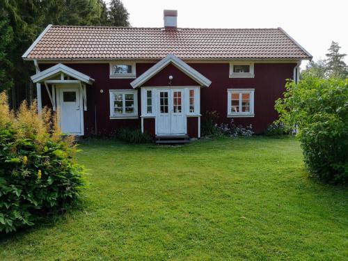 a red house with a white door and a yard at Torpet Norra Lundåsen in Fristad