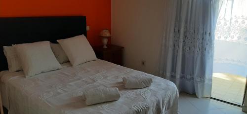 a bedroom with a white bed with two towels on it at Bela Alexandra Guest House in Fuzeta