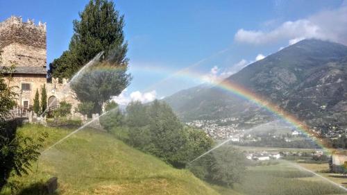 a rainbow over a field with a building and a mountain at B&B La Tour de Villa in Aosta