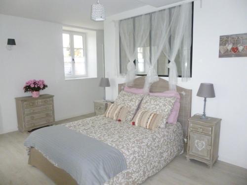 a bedroom with a bed with two night stands and two windows at Gîte de l’enclos in Menetou-Râtel
