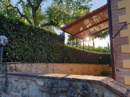 a stone retaining wall next to a fence with a pergola at Agriturismo Villino del Grillo in San Gimignano