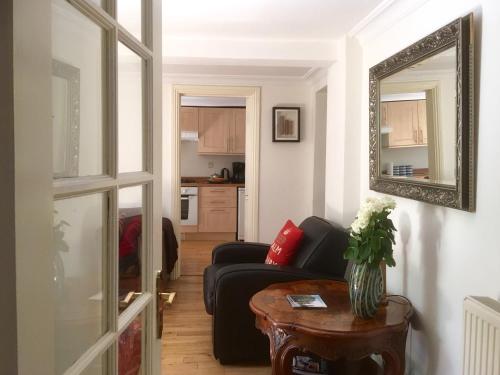een woonkamer met een zwarte bank en een spiegel bij Griffin House Holiday Apartments in Londen