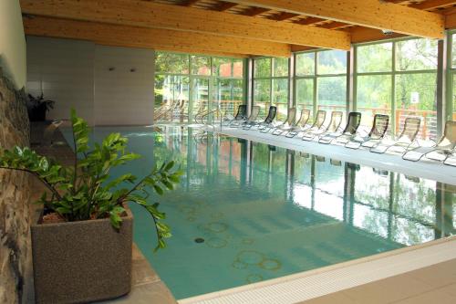 a swimming pool with chairs in a room with windows at Hotel Rusava 2 depandance in Rusava