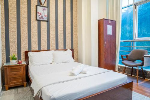 Un dormitorio con una cama y una silla y una ventana. en Aqua Kim Long Hotel, en Ho Chi Minh