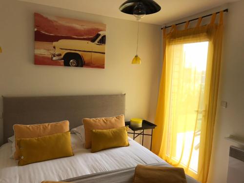 a bedroom with a bed with yellow pillows and a window at La maison d'Olivier in Honfleur
