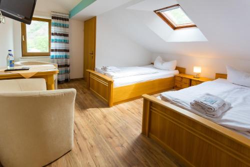 a room with two beds and a desk and a sink at Hotel & Ferienwohnungen Bohlenblick in Saalfeld