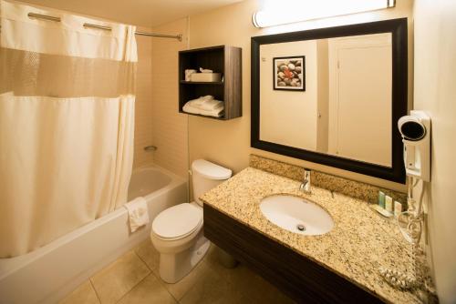 a bathroom with a sink and a toilet and a mirror at Quality Inn & Suites PE Trudeau Airport in Dorval