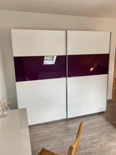 a large white cabinet in a room with a table at Steigerwaldblick Apartments Burgebrach in Burgebrach