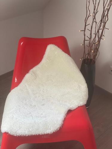a red chair with a white blanket on it at Steigerwaldblick Apartments Burgebrach in Burgebrach