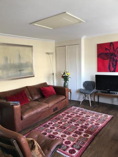 a living room with a brown couch and a rug at Griffin House Holiday Apartments in London