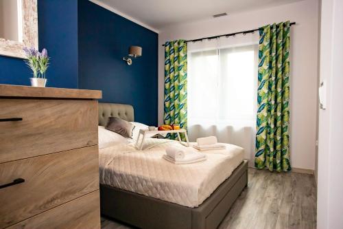 a bedroom with a bed with blue walls and a window at Willa Zdrojowa in Polańczyk