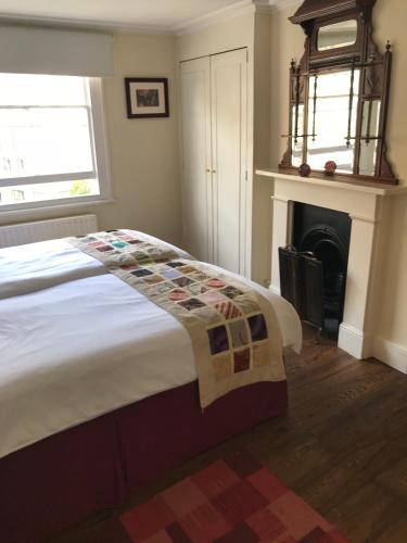 a bedroom with a bed with a fireplace and a clock at Griffin House Holiday Apartments in London