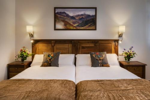 a bedroom with two beds and a painting on the wall at Hostal Bosque de Gamueta in Ansó