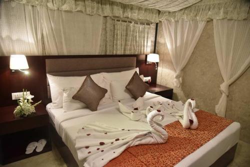 a bedroom with a bed with swans on it at Pride Hotel & Convention Centre Indore in Indore