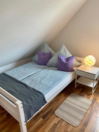 a bed with purple pillows on it in a room at Steigerwaldblick Apartments Burgebrach in Burgebrach