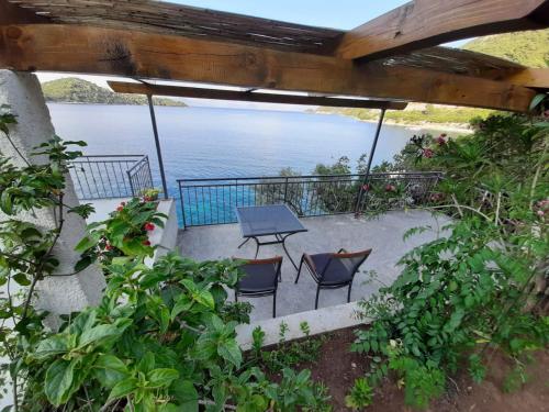 eine Terrasse mit Stühlen, einem Tisch und Wasser in der Unterkunft Guest House Matana in Sobra