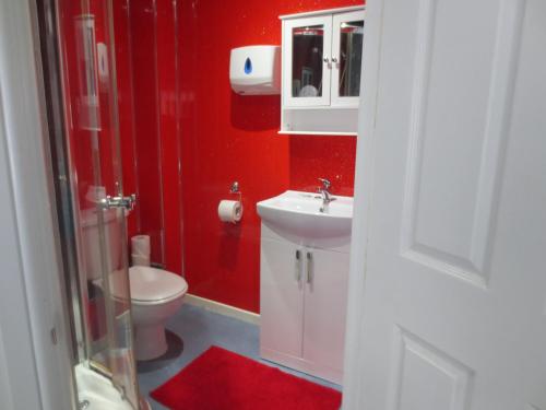 a red bathroom with a toilet and a sink at The Salendine in Blackpool