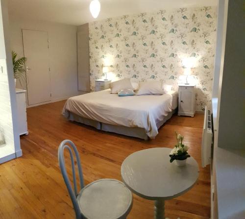 1 dormitorio con 1 cama, mesa y sillas en les chambres de Marthe, en Mesnay
