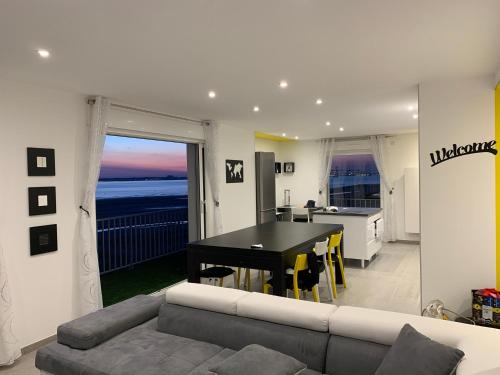 a living room with a couch and a table and a kitchen at Appartement "Envies D'ailleurs" Vue Mer in Saint-Brevin-les-Pins