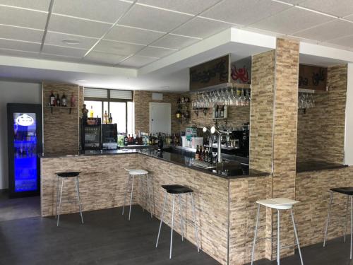 un bar con taburetes en una habitación con paredes de ladrillo en PENSION TASAGA en O Pino 