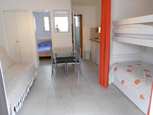 - une chambre avec des lits superposés, une table et une chaise dans l'établissement Marseillan Plage Les Ancres appartement 2 pièces près mer et commerces, à Marseillan