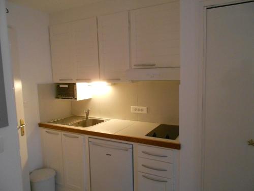 une petite cuisine avec des armoires blanches et un évier dans l'établissement Marseillan Plage Les Ancres appartement 2 pièces près mer et commerces, à Marseillan