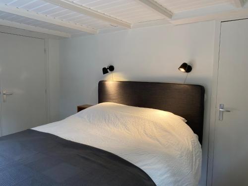 1 dormitorio con 1 cama con sábanas blancas y luces en t Melkhuisje - EV lader aanwezig! en Haaksbergen