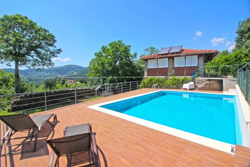 a swimming pool with chairs and a house at Casa Roupar by Gerês Casas in Terras de Bouro