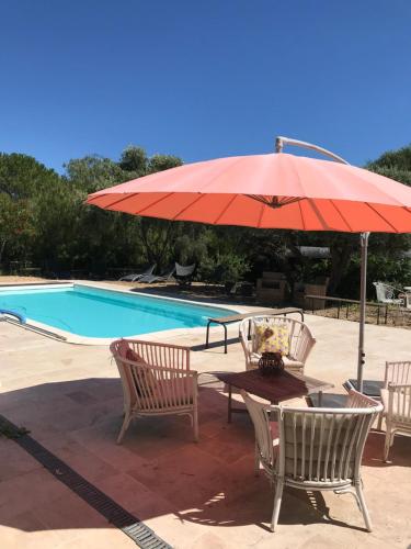 a table with a red umbrella next to a pool at les Chambres d'Amis in Sanary-sur-Mer