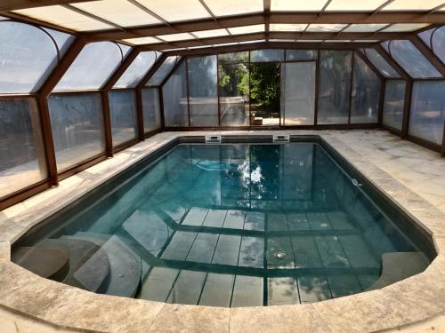 une piscine intérieure dans une serre avec fenêtres dans l'établissement Villa Muscat, piscine chauffée & spa, à Frontignan