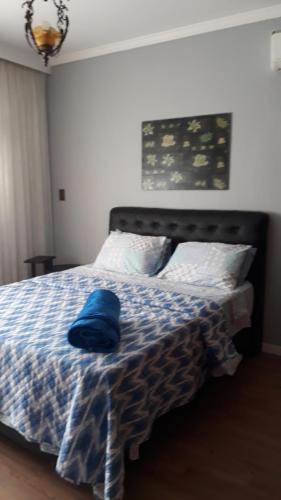 a bed with a blue hat sitting on top of it at Apartamento Gonzaga Santos in Santos