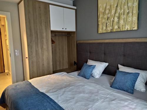 1 dormitorio con 1 cama grande con almohadas azules en Bel Mare Patio and Garden C106, en Międzyzdroje