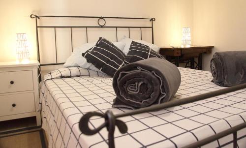 Una cama con almohadas blancas y negras y un sombrero. en Agriturismo dei girasoli, en Portoferraio