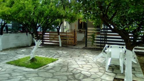 沃洛斯的住宿－Volos Traditional beach House 2，两把白色椅子坐在树下庭院