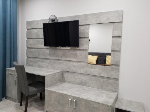 Zimmer mit einem Schreibtisch und einem TV an der Wand in der Unterkunft Новая и уютная квартира в центре in Uschhorod