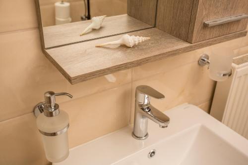 een wastafel in de badkamer met een spiegel en een zeepdispenser bij Pistakion Houses in Aegina Town