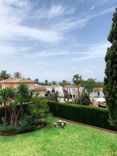 a yard with grass and palm trees and buildings at VILLA NABRISA MARBELLA, 5 BEDROOM, PRIVATE POOL, GARDEN, BBQ in Marbella