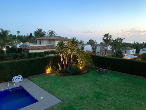 a backyard with a swimming pool and a house at VILLA NABRISA MARBELLA, 5 BEDROOM, PRIVATE POOL, GARDEN, BBQ in Marbella