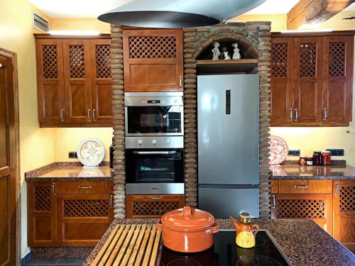 a kitchen with a stainless steel refrigerator and wooden cabinets at VILLA NABRISA MARBELLA, 5 BEDROOM, PRIVATE POOL, GARDEN, BBQ in Marbella