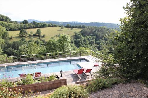 - une piscine avec 2 chaises rouges sur une terrasse dans l'établissement Les Terrasses de Labade Gîte et Chambres d'hôtes, à Coubisou
