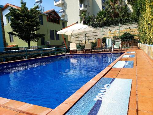 una gran piscina azul con bancos y sombrilla en Villa Angela, en Vlorë