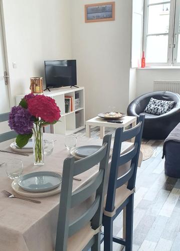 - un salon doté d'une table avec des assiettes et des fleurs dans l'établissement Escale dinannaise, à Dinan